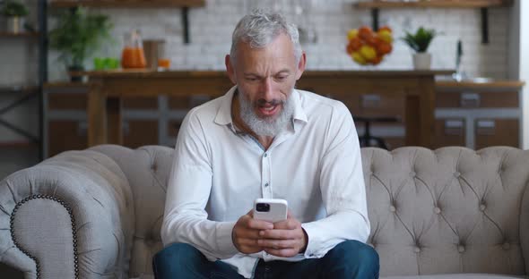 Amazed Happy Mature Businessman Receiving Message Reading Good News at Living Room