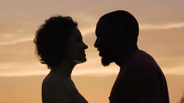 Silhouettes of Man and Woman Gently Touching Each Other Sunset Background