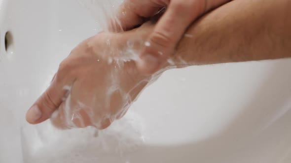 Man Washes His Hands with Liquid Soap in a Bathroom