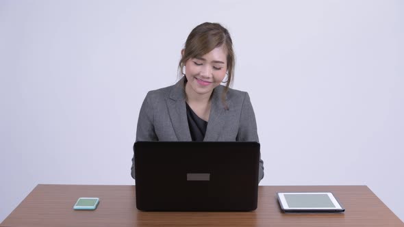 Young Happy Asian Businesswoman Thinking While Using Laptop at Work