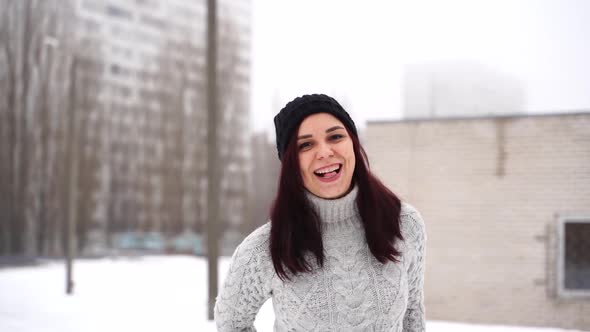 Young Beautiful Woman with Winter Cap and Gray Sweater Smiling and Laughing While Standing Outside