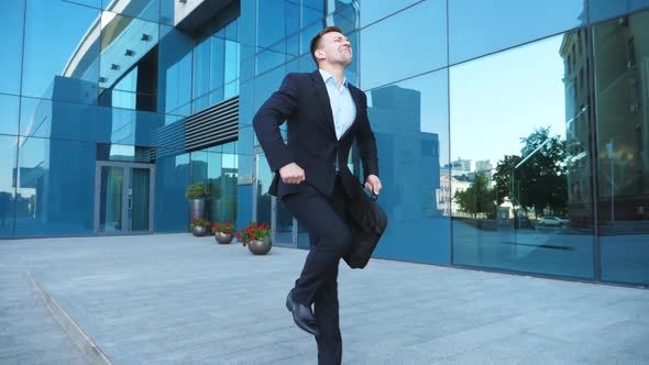 Young Happy Businessman in Suit Dances on City Street Celebrating Achievement