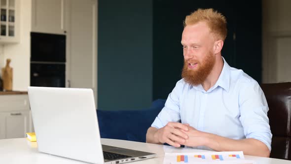 Optimistic Redhead Bearded Businessman Making Video Call on the Laptop