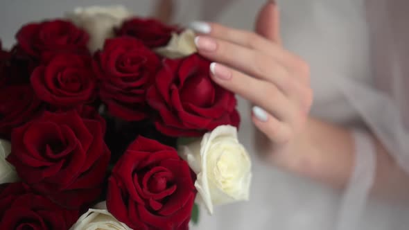 Wedding Bouquet of Red Roses in the Hands of the Bride