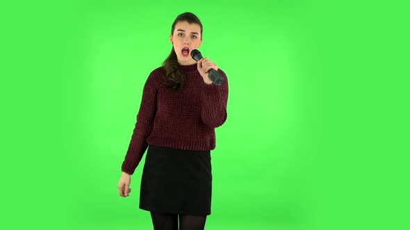 Attractive Girl Sings Into a Microphone and Moves To the Beat of Music. Green Screen