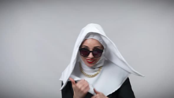 Cheerful Woman in Nun Costume and Sunglasses Dancing at Grey Background Having Fun Smiling