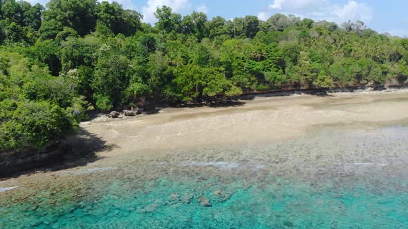 Aerial: flying over tropical Ai island white sand beach Banda Islands Indonesia