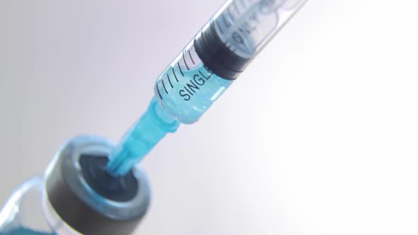 Dials Blue Coronavirus, Sars, Flu Vaccine Into Syringe on Light Background.