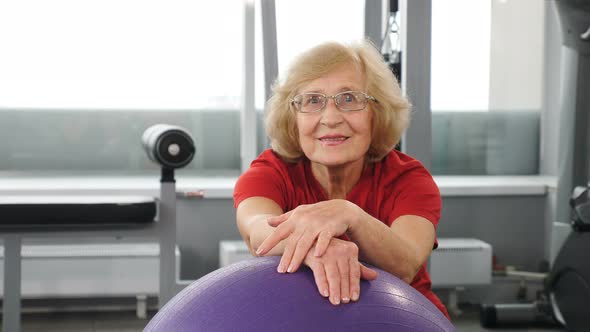 Portrait of Retired Pleasant Woman on Fitness Ball in Gym