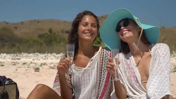 Two Smiling Girlfriends are Having the Tropical Beach Picnic They are Sitting on the Pink Sand with