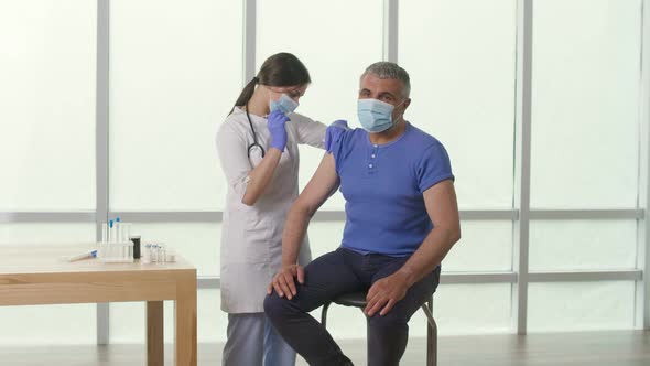 An Older Man Wearing a Protective Mask is Being Vaccinated Against