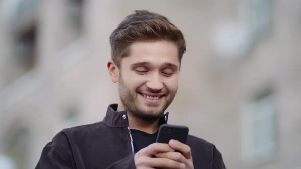 Smiling Guy Using Phone on Street, Happy Man Looking Phone Screen Outside