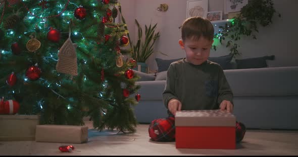 Happy Smiling Little Boy Opens His Christmas Gift From Santa Claus