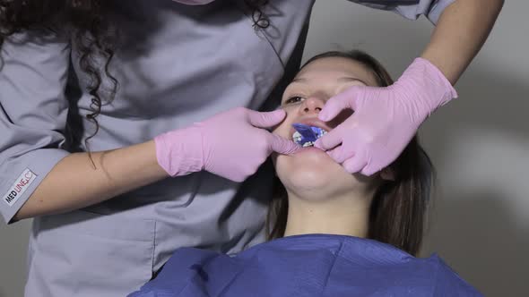 Orthodontist using dental impression tray on woman teeth