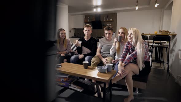 Young People Sitting on Settee and Watching TV