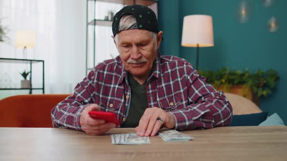 Smiling Senior Man Holding Money Cash and Smartphone Satisfied of Income Planning Family Budget