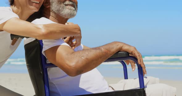 Side view of active senior African American woman embracing disabled senior man on the beach 4k