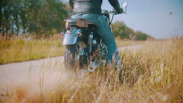 A Man Motorcyclist Starts Riding a Motorbike on the Road Surrounded By the Rye Field