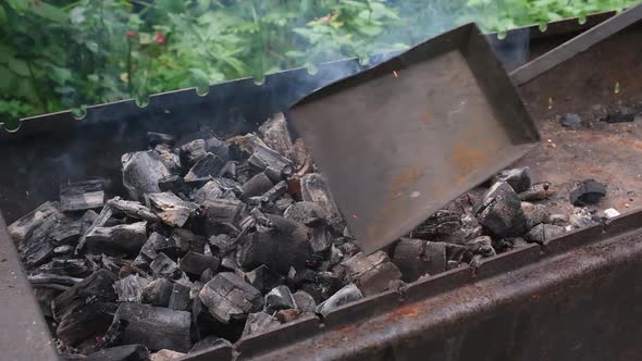 Burning coals and wood in the brazier turned over and prepared with coal shovel