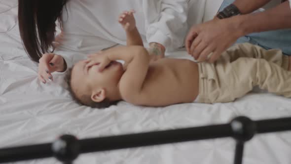 Happy Mixed Race Family Playing with Baby on the Bed