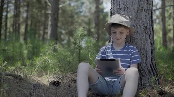 Boy using digital tablet in woods