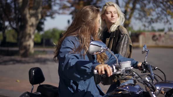 Two Millenial Girls Stand Up From Motorcycle on the City Street