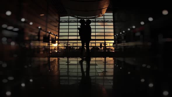 Silhouette of Man and a Woman They Say Goodbye in Airport Terminal