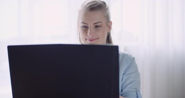 Smiling Woman Working on Laptop at Home Office. Businesswoman Typing on Computer Keyboard.