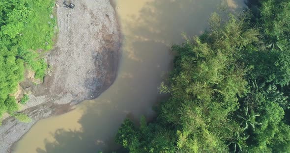 Big river with brown water surrounded by dense of trees. There are bamboo trees on the riverside. Ce