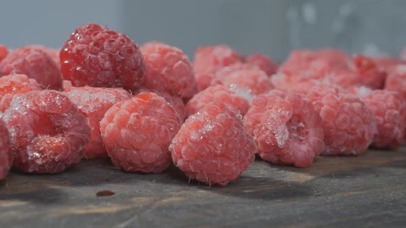 Frozen Raspberries Lies on a Wooden Board and a Gray Background. Close-up Dolly Video. Freezing