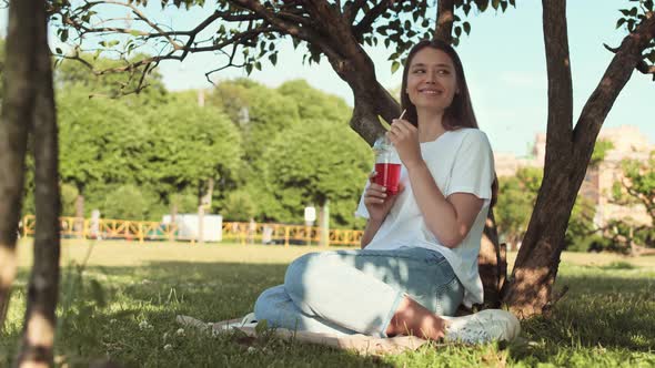 Woman Drinking Soda Sitting by Tree