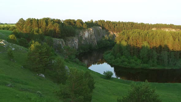 Aerial View of the River with a Rock and Forest on the Banks