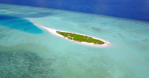 Remote tiny tropical island with lush vegetation and white sandy beach surrounded by turquoise azure