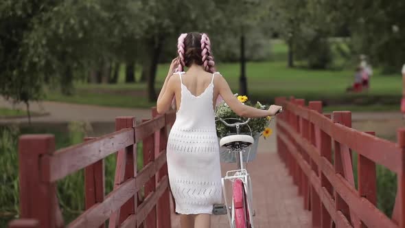 Romantic Sexy Girl in White Summer Dress Walking with Bicycle on Wooden Bridge at Forest Park