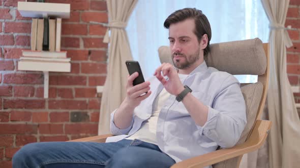 Casual Young Man Using Smartphone on Sofa