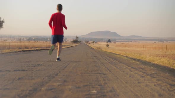 Man runs past on a gravel road during winter time