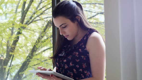 Beautiful woman using digital tablet near window