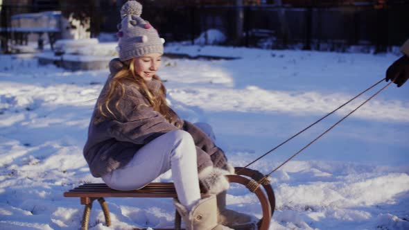 Smiling Young Girl Riding on Sleigh on Winter Vacation. Happy Teen Girl Sledding on Snow While