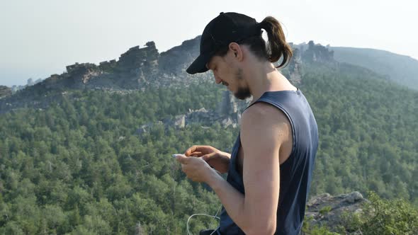 Woman in Sleeveless Shirt Points to Distant Steep Peaks