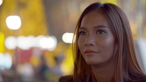 Attractive young woman in the city at night smiles at the camera - cinematic background bokeh light