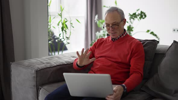 Smiling Senior Man Wave to Camera Having Video Call on Laptop
