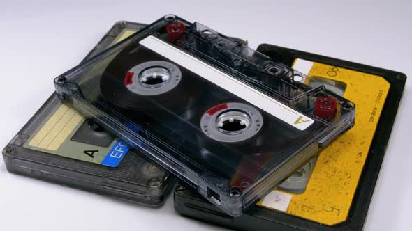 Three Vintage Audio Cassettes Rotate on White Background