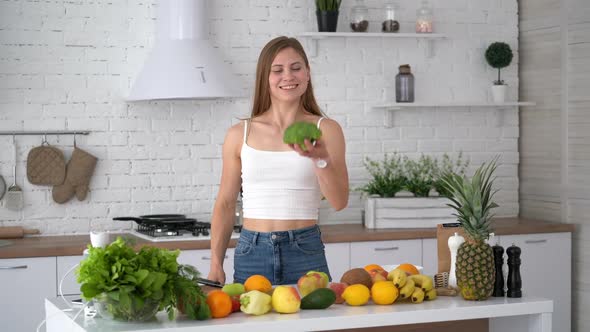 Healthy woman with sporty body in the kitchen. Attractive girl holding broccoli
