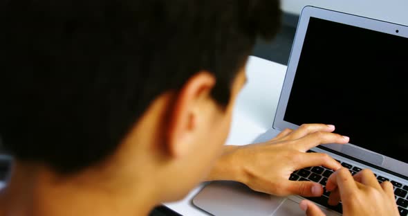 Students using digital tablet and laptop in classroom