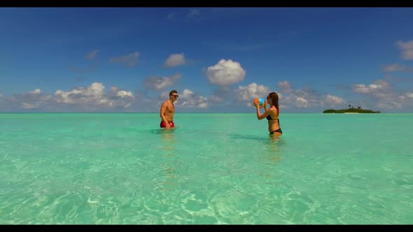 Two lovers relax on paradise island beach wildlife by blue ocean with white sandy background of the 