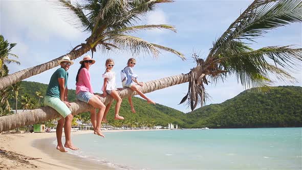 Young Family on Beach Vacation on Palm Tree. Parents and Kids Having Fun Together on the Coast of