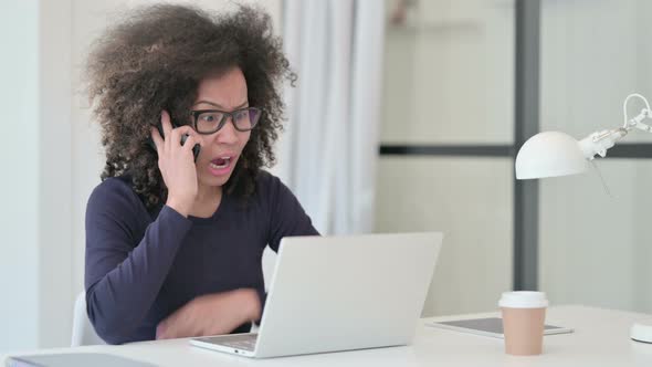 African Woman with Laptop Angry on Smartphone