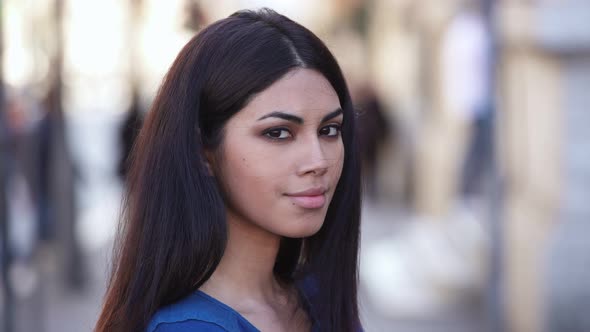 Beautiful young asian woman in the street turning her head and smiling at camera