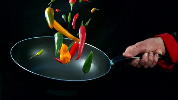 Super Slow Motion Shot of Chef Holding Frying Pan and Falling Chilli Peppers at 1000Fps