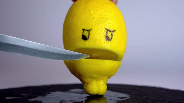 a kitchen knife and a yellow lemon cut in half with a stylized mouth and painted eyes
